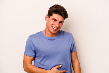 Obraz premium Young caucasian man isolated on white background touches tummy, smiles gently, eating and satisfaction concept.