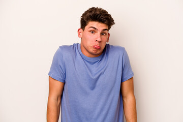 Young caucasian man isolated on white background shrugs shoulders and open eyes confused.