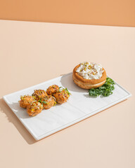 Vegan dinner in restaurant made from mushroom julienne in a bun  and baby potatoes on white plate on beige background