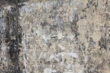 An old and dirty plaster wall texture. A weathered and damaged beige painted wall background.