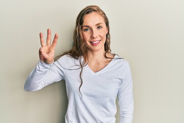 Fototapeta premium Young blonde woman wearing casual clothes showing and pointing up with fingers number three while smiling confident and happy.