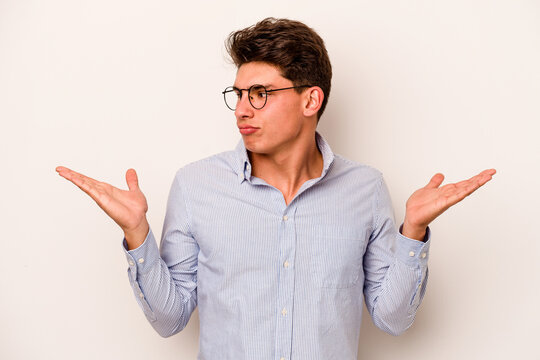 Young caucasian man isolated on white background confused and doubtful shrugging shoulders to hold a copy space.