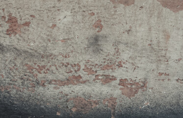 An old plaster wall with grunge texture. A weathered wall background with cracks in shades of grey, white and red.