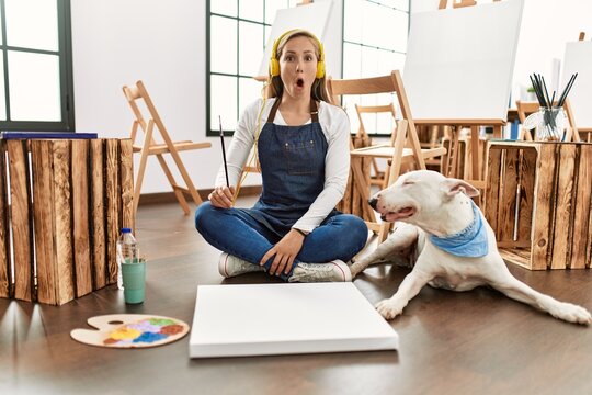 Caucasian young blonde woman at art studio scared and amazed with open mouth for surprise, disbelief face
