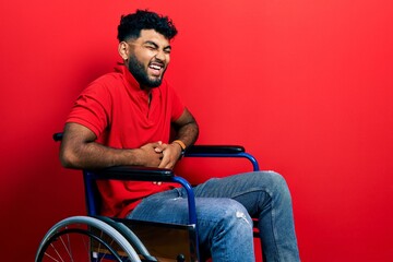 Arab man with beard sitting on wheelchair smiling and laughing hard out loud because funny crazy joke with hands on body.