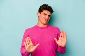 Young caucasian man isolated on blue background rejecting someone showing a gesture of disgust.