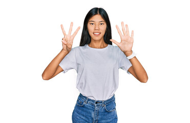 Beautiful young asian woman wearing casual white t shirt showing and pointing up with fingers number eight while smiling confident and happy.