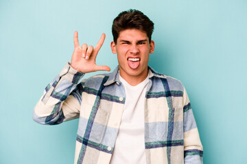 Naklejka premium Young caucasian man isolated on blue background showing rock gesture with fingers