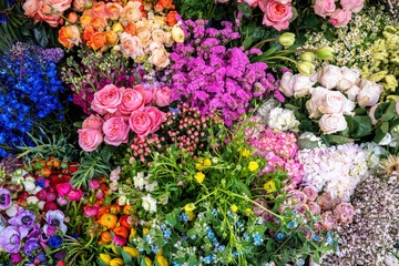 Beautiful background of flowers at a street market, a variety of colours and blooms including roses, anemones and tulips.