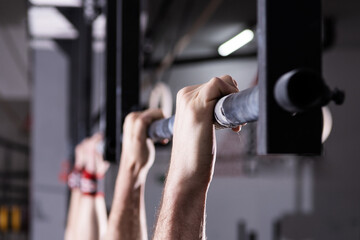 Close-up detail of male hands holding a pull-ups bar in a gym - obrazy, fototapety, plakaty