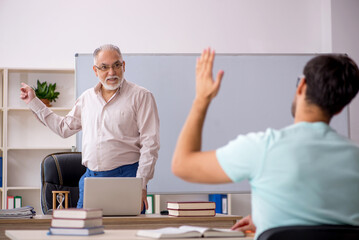 Old male teacher and young male student in the classroom