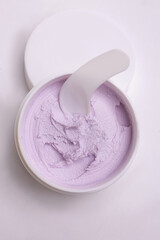 top view of a white jar of pink with a gentle face cream on a white background.