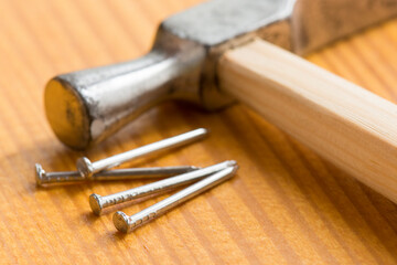 Carpenter hammer and small nails on a wooden worktable. Handmade master. Small carpentry work in the workshop. Home renovation.
