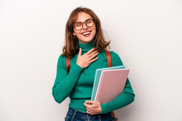 Young student caucasian woman isolated on white background laughs out loudly keeping hand on chest.