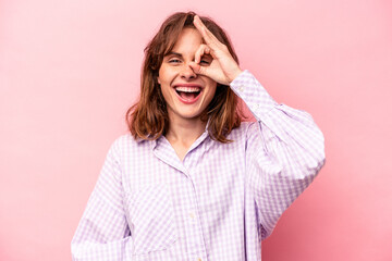 Young caucasian woman isolated on pink background excited keeping ok gesture on eye.