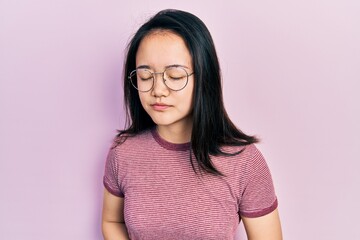 Young chinese girl wearing casual clothes and glasses with hand on stomach because indigestion,...