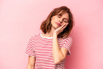 Young caucasian woman isolated on pink background who is bored, fatigued and need a relax day.