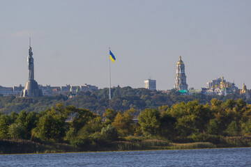 Aerial view of the Ukrainian flag waving in the wind against the city of Kyiv, Ukraine near the famous statue of Motherland.