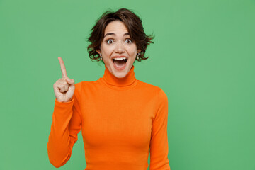 Young smiling insighted smart fun proactive woman 20s wear casual orange turtleneck holding index finger up with great new idea isolated on plain pastel light green color background studio portrait - obrazy, fototapety, plakaty