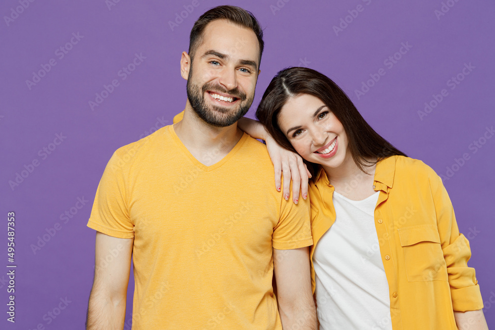 Wall mural Young happy smiling nice lovely couple two friends family man woman 20s together wear yellow casual clothes looking camera hud put head on shoulder isolated on plain violet background studio portrait