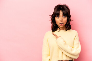 Young hispanic woman isolated on pink background pointing to the side