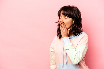 Young hispanic woman isolated on pink background being shocked because of something she has seen.