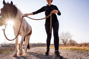 Low angle view of smiling woman and her beautiful pony walking toward camera on a beautiful sunny...
