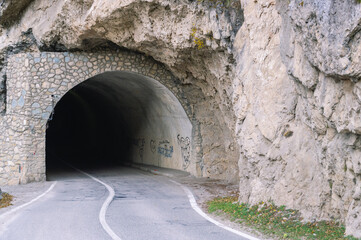 The tunnel for vehicles is laid in the mountains. A road for cars high in the mountains. Car headlights in the tunnel. The car drove into a tunnel in the mountains.