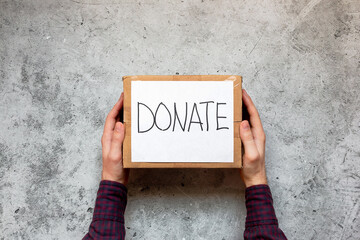 holds in his hands a box with humanitarian aid, donations, fundraising on a gray background