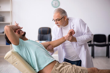 Obraz premium Young male patient visiting old male doctor
