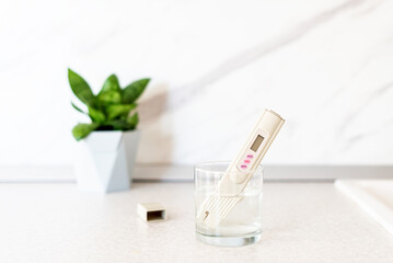 Glass of water, quality tester and universal litmus ph tester with color scale. Measuring the characteristics of drinking water. Tap water quality analyzer . Checking the purity of water at home