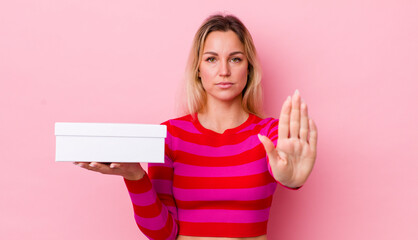 blonde pretty woman looking serious showing open palm making stop gesture. white box concept