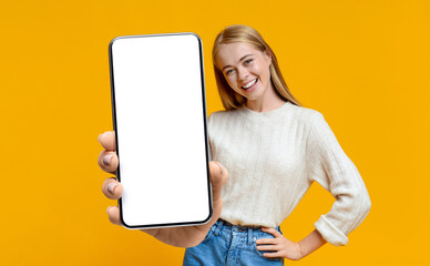 Excited woman demonstrating smartphone with blank white screen, showing space for your ad, website...