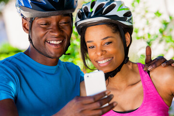 African American couple wearing bike helmets taking selfie
