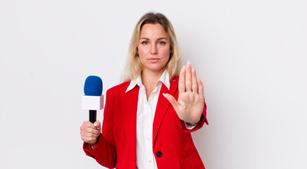 blonde pretty woman looking serious showing open palm making stop gesture. preporter and microphone...