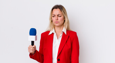 blonde pretty woman feeling sad, upset or angry and looking to the side. preporter and microphone...