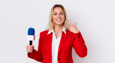 blonde pretty woman smiling confidently pointing to own broad smile. preporter and microphone...