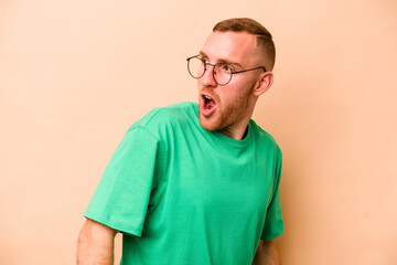 Obraz premium Young caucasian man isolated on beige background looks aside smiling, cheerful and pleasant.