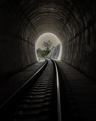 Fototapeta na wymiar Inside the railroad tunnel and railways with natural light at the end. Light at the end of the tunnel, Lights and shadows, Concept of achieving your goals, Copy space, Selective focus.