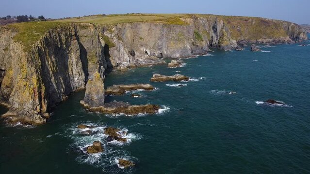 long majestic cliffs of the cooper coast, waterford ireland. in drone panning flight with azure water and calm sea of the atlantic.