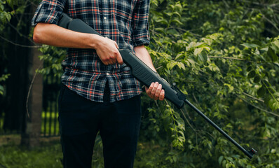 Young man with air pneumatic rifle, spring daytime, hands holding gun close up