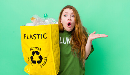 red head pretty woman looking surprised and shocked, with jaw dropped holding an object. recycling...