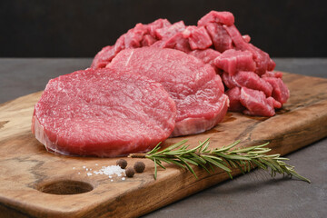 Fresh cut fillet of beef on a wooden board with salt, pepper, rosemary. Raw steak beef meat fillet ready to cook. Selective focus