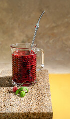 A cocktail of fresh raspberries and currants with a sprig of basil and a metal straw. Smoothies for healthy eating. The concept of a healthy lifestyle. Copy space.