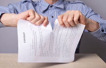 Man hands closeup breaking contract. Termination of agreement or employee dismissal concept. Man...