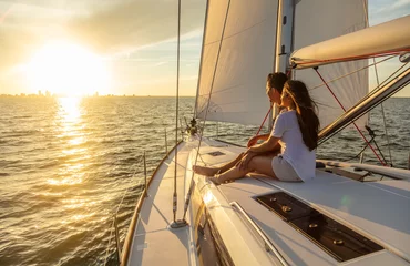 Fensteraufkleber Hispanic couple relaxing on private yacht at sunrise © Spotmatik