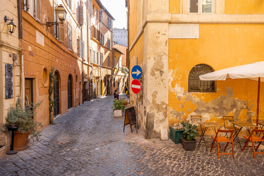 Fototapeta Narrow street with cafe and small shops in Rome. Italy travel concept, visiting cozy places