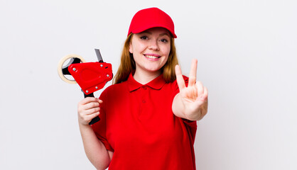 red head pretty woman smiling and looking friendly, showing number two. packer employee concept