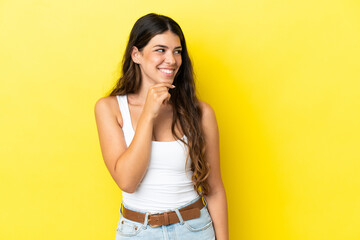 Young caucasian woman isolated on yellow background looking to the side and smiling