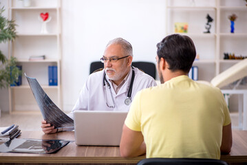 Obraz premium Young male doctor visiting old male doctor radiologist